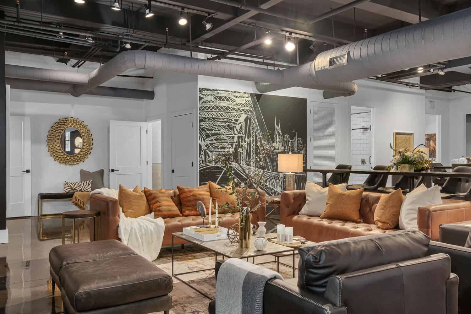 Modern living room with brown leather sofa, decorative pillows, and exposed ductwork.