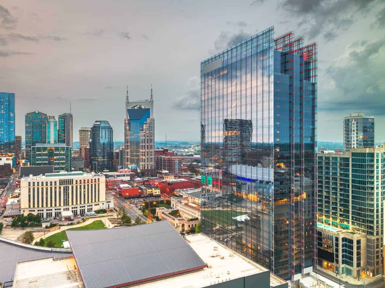 A cityscape with modern skyscrapers under a cloudy sky at dusk.