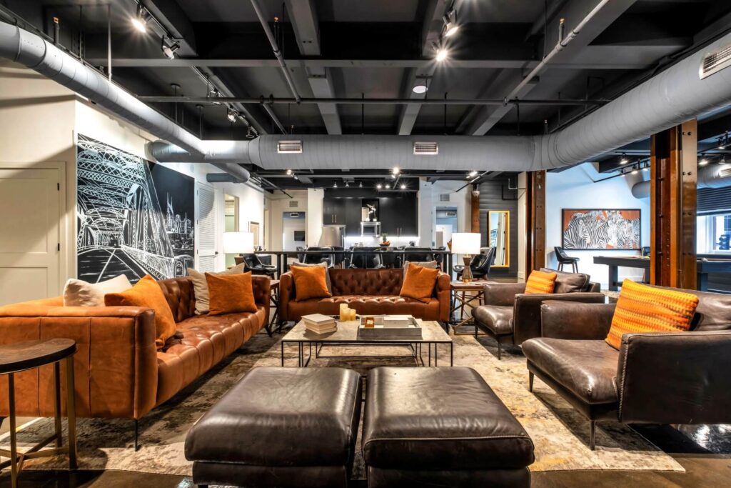 Modern office lounge with leather sofas, artwork, and industrial ceiling.