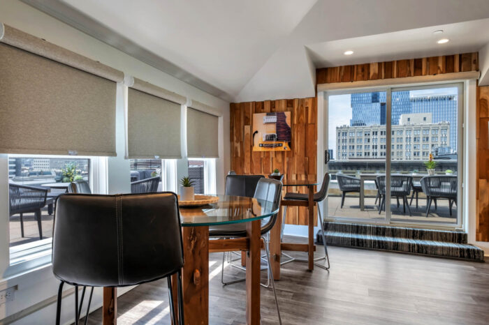 Modern dining area with glass table, city view from the balcony, and wooden accents.