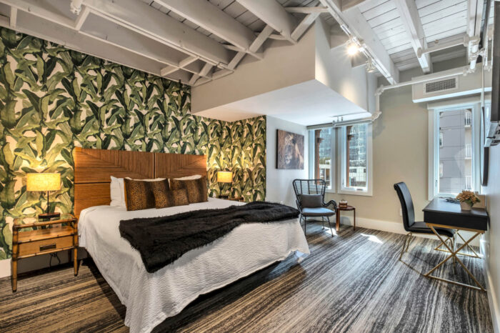 Modern bedroom with leaf-patterned wallpaper, exposed beams, and city view.