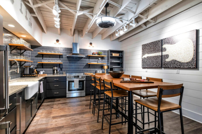 Modern kitchen with blue tiles, wooden dining table, and artistic wall decor.