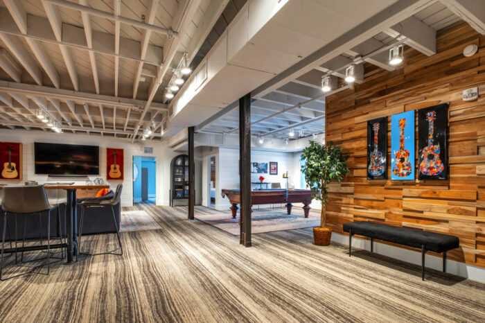 Modern office lounge with pool table, art on wood-paneled wall, and exposed beams.