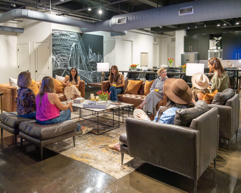 Group of people sitting in a modern living room setting with furniture and decor.
