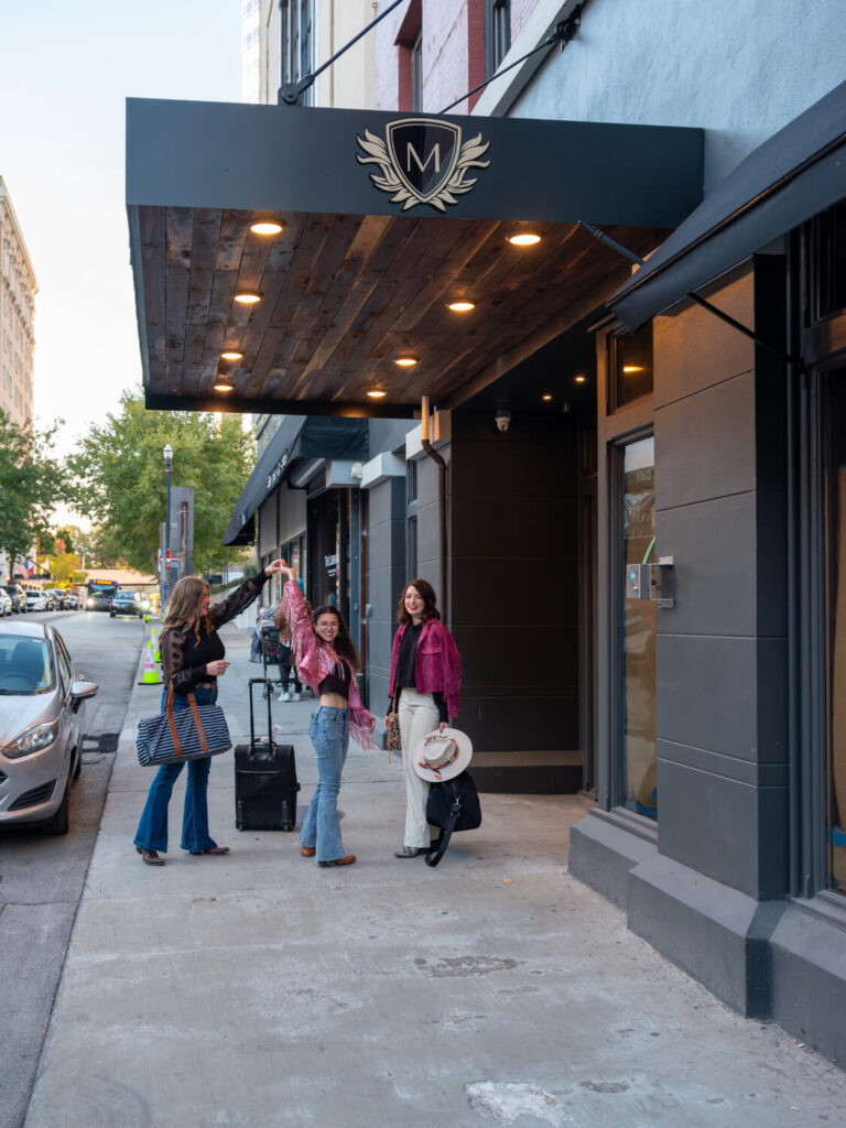 People standing under a lit awning outside a building at The Maddox Hotel.