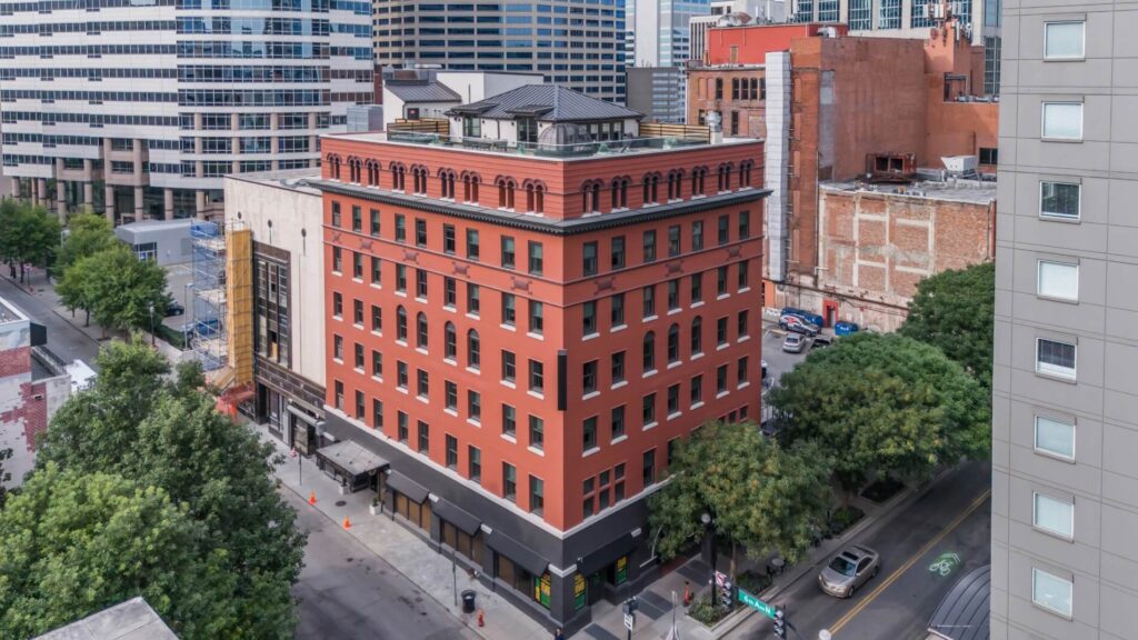 Aerial view of a red brick building among diverse architecture in an urban area.