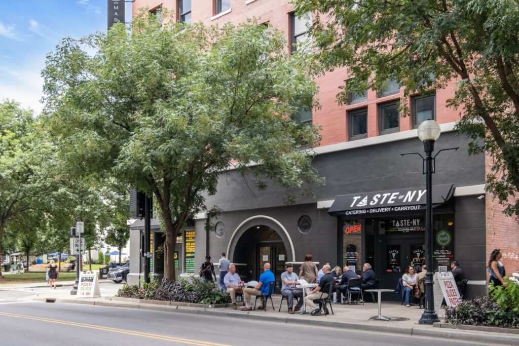 People seated at outdoor tables at a Taste NY cafe