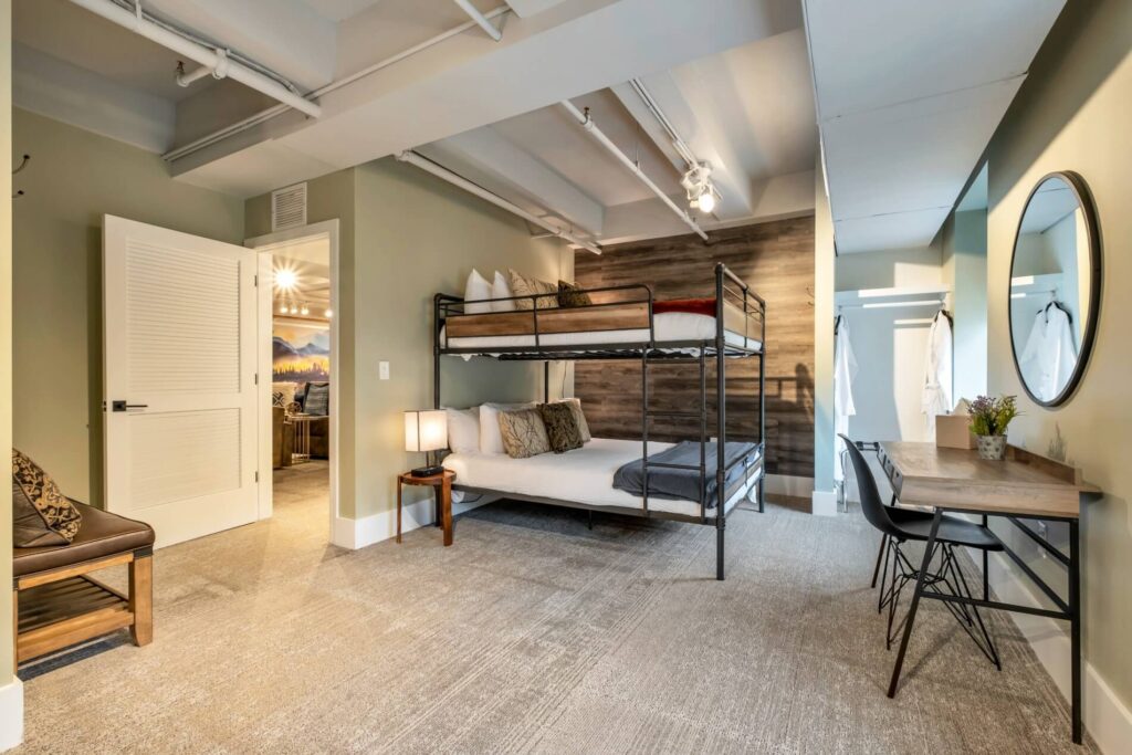 Modern room with bunk beds, wooden accents, a desk, and an open closet.