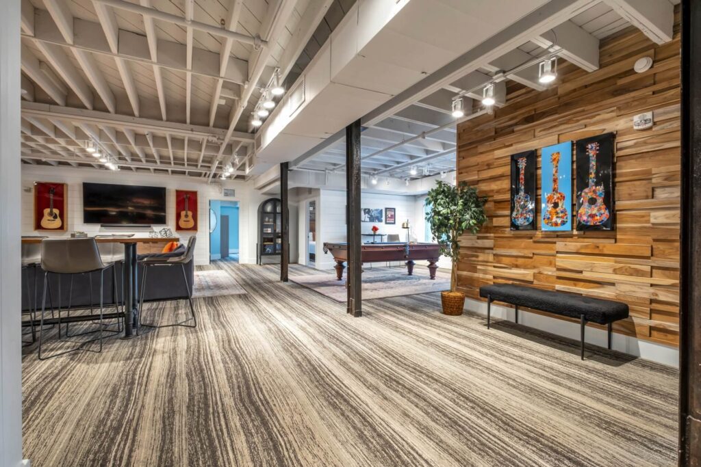 Modern office recreational space with pool table, guitars on the wall, and seating areas.