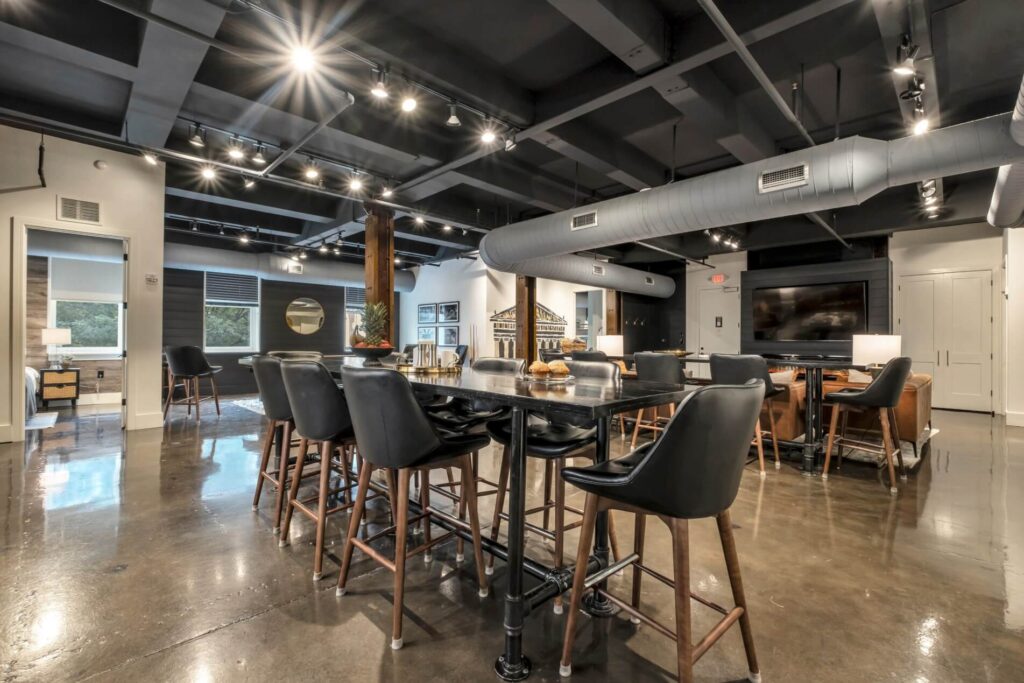 Modern office break room with a kitchenette, bar stools, and polished concrete floors.