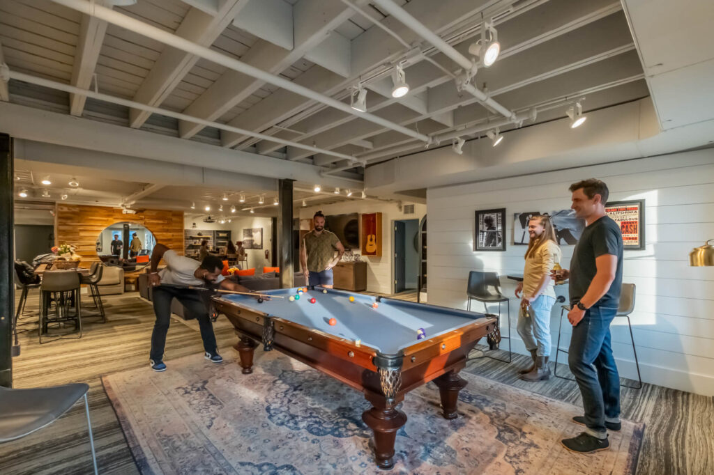 A cozy game room with individuals playing pool and conversing.