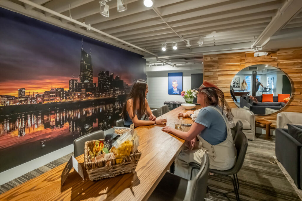 Two people sitting at a table in a modern room with a city skyline mural.