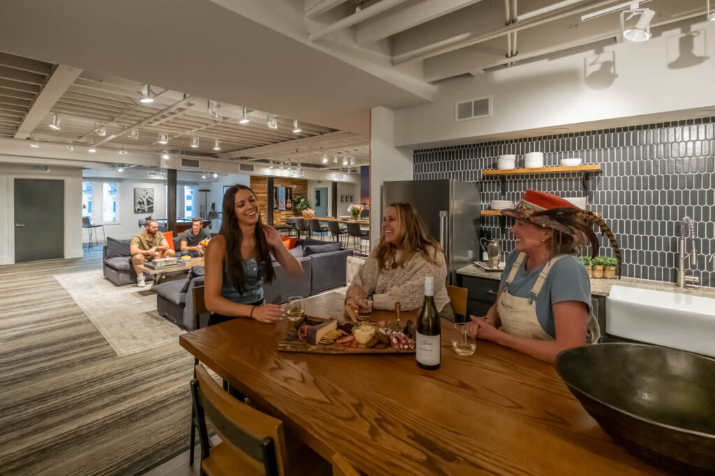 Modern kitchen bar with people, wine, and a charcuterie board.