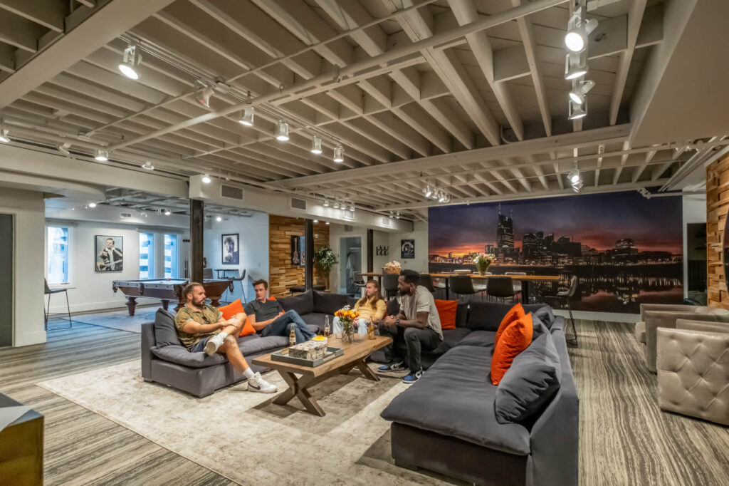 Modern lounge with sofas, pool table, and cityscape wall art.