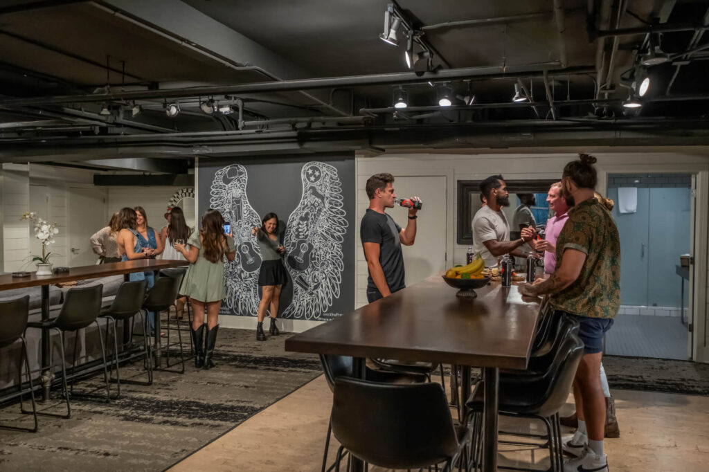 People socializing in a room with a winged mural on the wall.