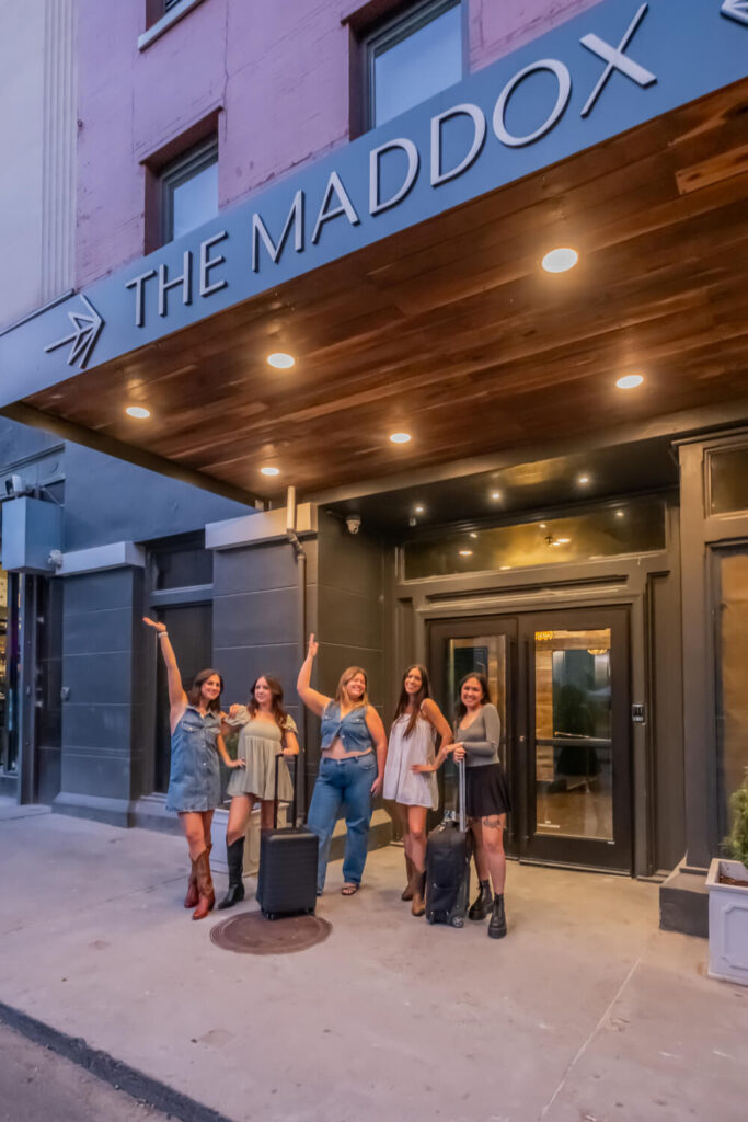 A group of people standing outside at The Maddox Hotel building entrance, pointing upwards.