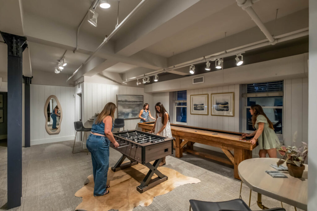 Modern game room with a foosball table, artwork on walls, and elegant lighting.
