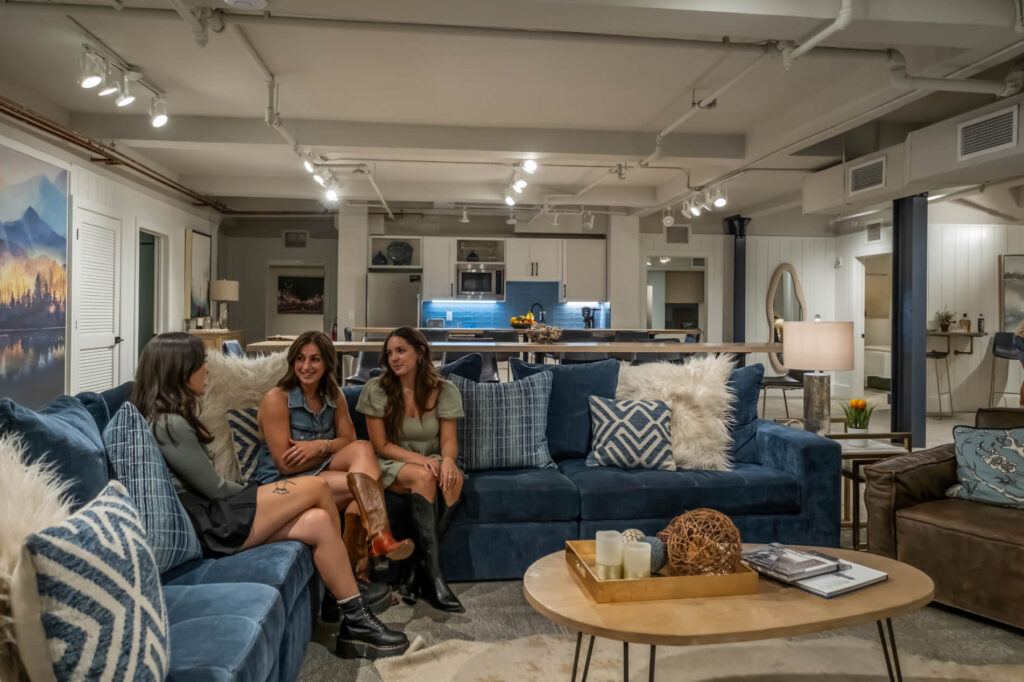 Cozy living room with blue sofa, modern decor, and an open kitchen in the background.