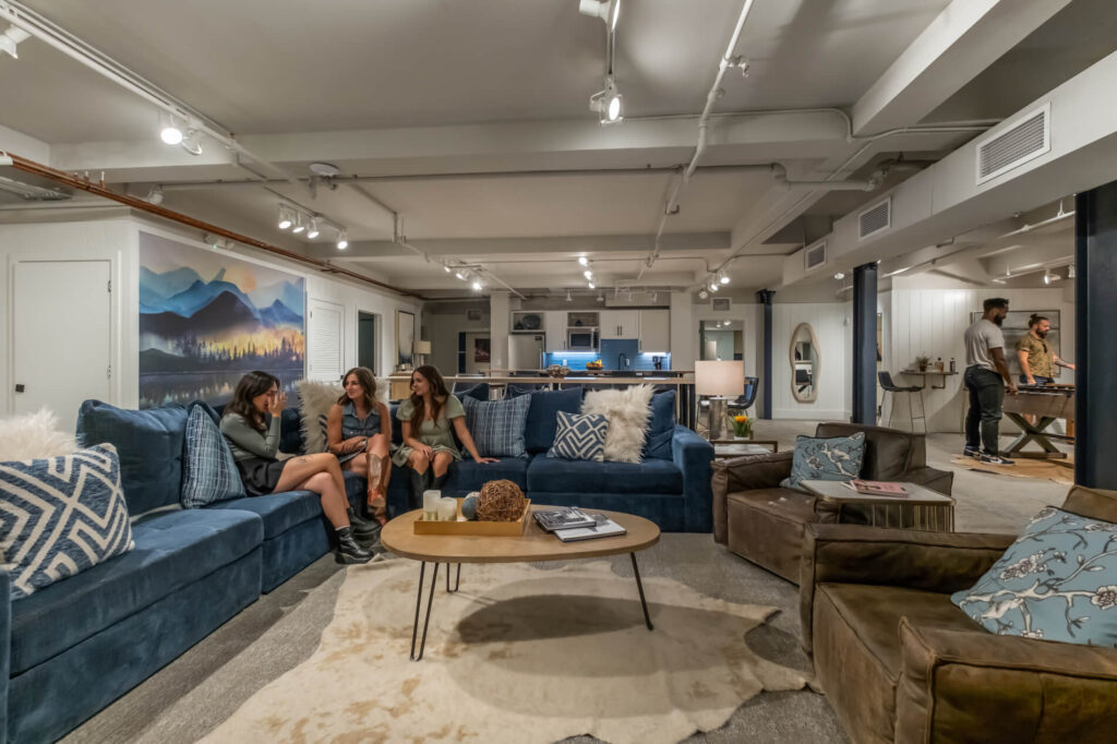 Modern living room with blue and brown sofas, a central table, and people in the background.