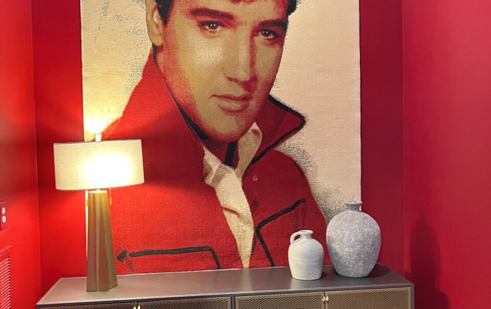 Elvis Presley tapestry in a red room with a console table and decorative items.